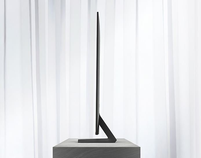 Thin flat-screen TV on stand against white curtains