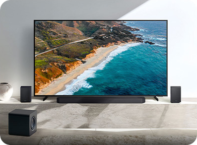 TV with soundbar and speakers showing beach scene